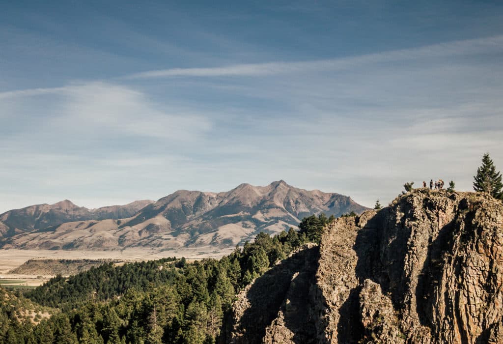 Hikers standing on a precipice in front of expansive mountain backdrop near Mountain Sky Guest Ranch