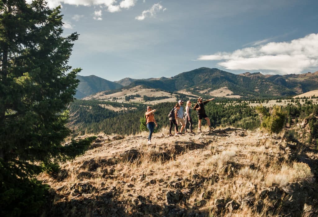 Group of hikers pointing at a sight in the distance with mountains behind them, near Mountain Sky property