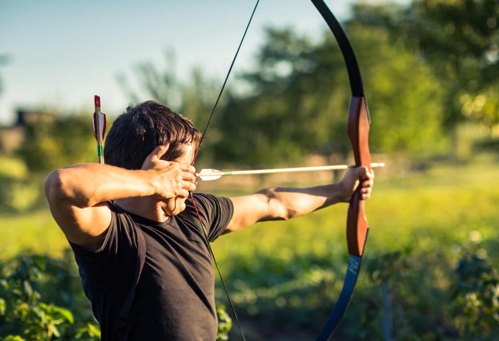 Man drawing an arrow in a bow with a quiver on this back